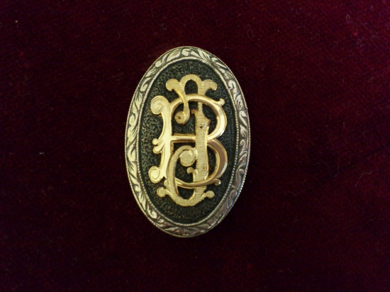 Striekorný medajlon so zlatým  monogramom na pištolovu rukoveť pažby.
